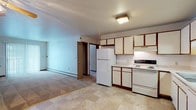 This single-floor residence offers a practical and functional layout with a straightforward design suited for comfortable everyday living. The kitchen anchors one end of the open-concept main area and is outfitted with white cabinetry accented by warm wood-toned trim, a full suite of white appliances including a refrigerator, electric range, and dishwasher, and tile flooring in a neutral stone pattern. Ample upper and lower cabinet storage is complemented by under-cabinet lighting over the range area. The kitchen flows seamlessly into the living space, which transitions to carpeted flooring and features a ceiling fan with integrated lighting, baseboard heating, and a sliding glass door that allows natural light to filter in.

The bedrooms are carpeted and well-proportioned, with each room benefiting from natural light provided by multiple windows. Ceiling fans are present in at least one bedroom. Closet storage is notably generous, with one bedroom featuring two separate bi-fold closets side by side, and another offering a single reach-in closet. The bathroom includes tile flooring consistent with the kitchen, a full tub-shower combination, a vanity with storage, and clean, neutral finishes throughout. Overall, the unit presents a clean, move-in ready environment with consistent warm-toned trim details unifying the space.