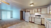 This single-floor residence offers a practical and functional layout with a straightforward design suited for comfortable everyday living. The kitchen anchors one end of the open-concept main area and is outfitted with white cabinetry accented by warm wood-toned trim, a full suite of white appliances including a refrigerator, electric range, and dishwasher, and tile flooring in a neutral stone pattern. Ample upper and lower cabinet storage is complemented by under-cabinet lighting over the range area. The kitchen flows seamlessly into the living space, which transitions to carpeted flooring and features a ceiling fan with integrated lighting, baseboard heating, and a sliding glass door that allows natural light to filter in.

The bedrooms are carpeted and well-proportioned, with each room benefiting from natural light provided by multiple windows. Ceiling fans are present in at least one bedroom. Closet storage is notably generous, with one bedroom featuring two separate bi-fold closets side by side, and another offering a single reach-in closet. The bathroom includes tile flooring consistent with the kitchen, a full tub-shower combination, a vanity with storage, and clean, neutral finishes throughout. Overall, the unit presents a clean, move-in ready environment with consistent warm-toned trim details unifying the space.