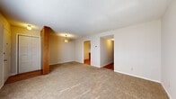 Located at 3100 Heritage Ct in Manhattan, Kansas, this one-bedroom, one-bathroom unit offers a thoughtfully organized single-floor layout designed for efficient everyday living. The space is organized around a central hallway that connects the living room, kitchen, bedroom, and bathroom.

The living room is carpeted and open in feel, with neutral beige walls, a textured ceiling, and a pendant light fixture. Doorways lead directly to both the kitchen and the hallway, creating a connected flow throughout the unit. The kitchen features warm-toned oak cabinetry, white laminate countertops, a white tile backsplash, and hardwood-style flooring. A full suite of white appliances includes an electric range with over-the-range microwave, refrigerator, and dishwasher, complemented by a pendant light above the sink area.

The bedroom is a generously sized, carpeted room featuring a ceiling fan with light, a window with blinds for natural light, and a closet with a wood-panel door. The bathroom includes a vanity with wood cabinetry, a mirror, and a full tub-shower combination with white tile surround. Throughout the unit, textured ceilings and neutral tones create a clean, understated aesthetic.