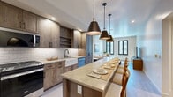 Located at 2777 W Sandalwood Dr in Lehi, Utah, this thoughtfully designed one-bedroom, one-bathroom residence offers an efficient and stylish single-level layout. The open-concept kitchen and living area serves as the heart of the home, where rich wood cabinetry, a white subway tile backsplash, stainless steel appliances, a farmhouse sink, and a generously sized island with pendant lighting create a refined yet functional culinary space. Light wood-tone flooring flows throughout, contributing to the warm, cohesive aesthetic. The living room is bright and inviting, featuring black-framed windows that draw in natural light and offer views of the surrounding community, complemented by track lighting above. The primary bedroom is a comfortable retreat with plush carpeting, black-framed French doors opening to a private balcony, and direct access to the hallway and closet. The walk-in closet offers a combination of open wood shelving and wire rack storage. The bathroom is elegantly finished with a wood-toned vanity, LED-lit mirror, subway tile surround, and a stacked in-unit Whirlpool washer and dryer tucked neatly into a dedicated closet. Throughout the space, neutral tones and modern hardware create a clean, contemporary ambiance.