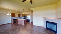 Located in Spokane, WA, this two-story residence at North Indian Trail Road offers a well-designed layout that balances functionality and comfort throughout both levels. The main floor sets a welcoming tone with durable hardwood-style flooring that flows seamlessly from the entry foyer—highlighted by a wood-railed staircase with carpeted treads—through to the open-concept kitchen and living area.

The kitchen is a standout feature, equipped with warm-toned wood cabinetry, light stone countertops, a subway tile backsplash, and a full suite of stainless steel appliances including a refrigerator, range, microwave, and dishwasher. A central island provides additional prep and seating space, while pendant lighting and a decorative chandelier add character. The adjacent living area features a brick-surround fireplace and a ceiling fan, creating a cohesive and inviting gathering space.

A dedicated laundry area includes upper cabinetry and utility hookups for added convenience. The bathrooms are finished with wood vanities, tile accents, and sliding glass shower enclosures. Upper-level bedrooms are carpeted and receive natural light through windows with views of the surrounding neighborhood and treeline, contributing to a calm residential atmosphere throughout.