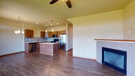 Located in Spokane, WA, this two-story residence at North Indian Trail Road offers a well-designed layout that balances functionality and comfort throughout both levels. The main floor sets a welcoming tone with durable hardwood-style flooring that flows seamlessly from the entry foyer—highlighted by a wood-railed staircase with carpeted treads—through to the open-concept kitchen and living area.

The kitchen is a standout feature, equipped with warm-toned wood cabinetry, light stone countertops, a subway tile backsplash, and a full suite of stainless steel appliances including a refrigerator, range, microwave, and dishwasher. A central island provides additional prep and seating space, while pendant lighting and a decorative chandelier add character. The adjacent living area features a brick-surround fireplace and a ceiling fan, creating a cohesive and inviting gathering space.

A dedicated laundry area includes upper cabinetry and utility hookups for added convenience. The bathrooms are finished with wood vanities, tile accents, and sliding glass shower enclosures. Upper-level bedrooms are carpeted and receive natural light through windows with views of the surrounding neighborhood and treeline, contributing to a calm residential atmosphere throughout.