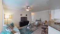 This single-story, 2-bedroom, 2-bathroom residence offers a thoughtfully designed layout with comfortable living spaces and quality finishes throughout. Crown molding accents the ceilings in the living and bedroom areas, lending a refined touch to the warm, neutral color palette that flows through each room.

The living room features plush carpeting, a ceiling fan with integrated lighting, and a large window that invites natural light. It connects seamlessly to a dedicated dining area, which benefits from its own window overlooking greenery outside. The kitchen is equipped with stainless steel appliances—including a dishwasher and over-range microwave—granite-style countertops, white cabinetry, and hardwood-style flooring that extends into the dining space.

The primary bedroom is generously proportioned with carpet, crown molding, a ceiling fan, and direct access to a walk-in closet. Its en-suite bathroom features a long vanity with ample cabinet storage and hardwood-style flooring. The second bedroom also includes a ceiling fan, carpet, and natural light from a large window. A second full bathroom offers a soaking tub with full tile surround. The layout provides a practical, comfortable flow throughout.