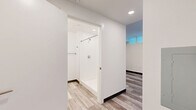 Located at 1275 N Santa Fe Dr in Denver's vibrant Santa Fe Arts District, this efficiently designed single-floor unit offers a thoughtfully laid-out living space that maximizes every square foot. The open-concept interior is finished with light wood-tone plank flooring throughout, lending a clean, contemporary feel that ties the entire space together.

The kitchen is a standout feature, showcasing sleek gray flat-front cabinetry extending from floor to ceiling, contrasted by crisp white countertops and a white tile backsplash. A full suite of stainless steel appliances — including a refrigerator, electric range, built-in microwave, and dishwasher — makes this kitchen as functional as it is stylish. Recessed lighting illuminates the space from above.

The bathroom continues the modern aesthetic with matching gray cabinetry, a white countertop vanity, wood-look plank flooring, and a walk-in tiled shower equipped with a grab bar, combining accessibility with clean design.

A bright, open living area leads to a private balcony through a floor-to-ceiling glass sliding door framed in sleek black, inviting generous natural light and providing a seamless indoor-outdoor connection. White walls and recessed lighting throughout the unit create a bright, airy ambiance well-suited for contemporary urban living.