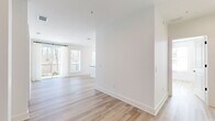 Located at 2490 N Druid Hills Rd in Atlanta, GA, this well-appointed single-floor residence offers three bedrooms and three full bathrooms thoughtfully arranged for comfortable living. Light-toned hardwood flooring flows consistently throughout, lending a clean, cohesive aesthetic to every room. The open-concept kitchen and living area serves as the heart of the home, featuring warm wood cabinetry, dark countertops, a central island with an undermount sink, stainless steel appliances, and globe pendant lighting. Multiple windows flood the space with natural light and provide pleasant views of surrounding greenery. The living area opens to a private balcony through sliding glass doors dressed with sheer white curtains, extending the living space outdoors. Each bedroom is generously proportioned with large windows that frame wooded outdoor views. The primary bedroom includes access to a well-organized walk-in closet with built-in shelving and a private en-suite bathroom featuring a floor-to-ceiling tiled glass-enclosed shower. Additional closets with built-in organization systems provide ample storage. The overall design is modern and minimalist, with crisp white walls, clean lines, and an abundance of natural light creating a bright and welcoming atmosphere throughout.