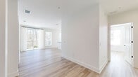 Located at 2490 N Druid Hills Rd in Atlanta, GA, this well-appointed single-floor residence offers three bedrooms and three full bathrooms thoughtfully arranged for comfortable living. Light-toned hardwood flooring flows consistently throughout, lending a clean, cohesive aesthetic to every room. The open-concept kitchen and living area serves as the heart of the home, featuring warm wood cabinetry, dark countertops, a central island with an undermount sink, stainless steel appliances, and globe pendant lighting. Multiple windows flood the space with natural light and provide pleasant views of surrounding greenery. The living area opens to a private balcony through sliding glass doors dressed with sheer white curtains, extending the living space outdoors. Each bedroom is generously proportioned with large windows that frame wooded outdoor views. The primary bedroom includes access to a well-organized walk-in closet with built-in shelving and a private en-suite bathroom featuring a floor-to-ceiling tiled glass-enclosed shower. Additional closets with built-in organization systems provide ample storage. The overall design is modern and minimalist, with crisp white walls, clean lines, and an abundance of natural light creating a bright and welcoming atmosphere throughout.