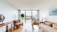 Located on W First St N in the heart of downtown Wichita, KS, this well-appointed one-bedroom, one-bathroom residence offers a thoughtful layout across a single floor. The living room immediately impresses with expansive floor-to-ceiling windows that flood the space with natural light and frame sweeping panoramic views of the Wichita skyline. Light hardwood flooring runs throughout the living area, complementing the neutral-toned walls and creating a bright, airy atmosphere. The kitchen features warm oak cabinetry, a dishwasher, ample counter space, and a pass-through bar with seating for three — ideal for casual dining or entertaining. The bedroom is generously proportioned, continuing the floor-to-ceiling window theme with stunning cityscape views and carpeted flooring for added comfort. It includes a mirrored sliding-door closet, providing convenient storage. A hallway connects the main living areas to the full bathroom, which includes a single-sink vanity with oak cabinetry, tile flooring, and a shower/tub combination. Throughout the unit, the design balances practicality with an elevated urban aesthetic, making it a compelling residence in the heart of downtown Wichita.