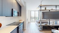 This 310 square foot apartment in Miami, FL offers a compact yet stylish living space. The single-floor layout includes one bedroom, one bathroom, and a kitchen, efficiently designed to maximize the available area. The primary bedroom, measuring 110 square feet, features a large floor-to-ceiling sliding glass door that floods the space with natural light and provides stunning city views.

The modern design aesthetic is evident throughout the apartment. The bedroom showcases a neutral color palette with a plush, upholstered headboard and built-in side tables. The bathroom, while compact, boasts a clean, contemporary look with a wooden ladder for towel storage and coastal-inspired artwork.

The kitchen is a highlight, featuring sleek dark cabinetry contrasted with white countertops and backsplash. Stainless steel appliances, including a built-in microwave and oven, add a touch of sophistication. The light wood flooring throughout the apartment creates a sense of continuity and warmth.

Despite its small footprint, the apartment feels spacious due to its thoughtful design and use of light colors. The large windows not only provide views but also create an illusion of more space. This urban dwelling, located at 153 NW 24th St in Miami, offers a perfect blend of style and functionality for city living.
