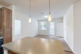 This 2-bedroom, 2-bathroom residence offers a thoughtfully designed single-level layout that maximizes comfort and functionality. The open-concept living area seamlessly connects the kitchen, dining, and living spaces, creating a bright and airy atmosphere. The kitchen is a standout feature, showcasing warm wood cabinetry, granite-style countertops, a central island with pendant lighting, and black appliances including a range, microwave, refrigerator, and dishwasher. Hardwood-style flooring runs throughout the kitchen and dining areas, while plush carpeting provides comfort in the living room and bedrooms. Natural light flows in through multiple windows, including a sliding glass door that leads to a private balcony, offering outdoor views. The spacious primary bedroom includes a generous walk-in closet with wire shelving, providing ample storage. Both bathrooms are appointed with wood-toned vanities, granite-style countertops, and tub-shower combinations. A second well-sized bedroom with carpeted flooring and a window rounds out the sleeping quarters. A dedicated laundry area and two closets add to the home's practical appeal, making this a complete and comfortable living space.