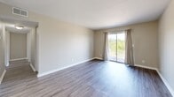 Located at 3130 Saint Anthony Gardens Dr in Louisville, Kentucky, this 2-bedroom, 2-bathroom single-floor residence offers a clean, modern aesthetic throughout. Wood-look plank flooring flows consistently across all rooms, complemented by neutral warm-beige walls and crisp white trim that create a bright, cohesive atmosphere.

The open living room is a standout feature, showcasing sliding glass doors framed by drape panels that invite natural light and offer outdoor views of surrounding greenery. A stylish sputnik-style chandelier adds a contemporary touch as the living space transitions toward the kitchen. The galley-style kitchen is well-appointed with white shaker cabinetry, granite countertops, a subway tile backsplash, stainless steel appliances including a refrigerator, range, microwave, and dishwasher, and a pendant light fixture overhead.

Both bedrooms are comfortably sized, with the primary bedroom offering a generously proportioned layout. Each bedroom benefits from natural light through windows with views of the surrounding neighborhood. The two bathrooms are finished with white vanity cabinetry, granite countertops, lighted mirrors, and wood-look tile flooring. A hallway connects the bedrooms and bathrooms, providing a practical and well-organized layout throughout this efficiently designed residence.