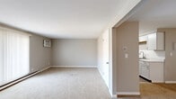 Located at 85 Paradise Ln in Tonawanda, NY, this single-floor, two-bedroom, one-bathroom unit offers a functional and well-organized layout across a comfortable footprint. The interior is finished with neutral-toned walls and wall-to-wall carpet throughout the living spaces and bedrooms, creating a warm and cohesive aesthetic.

The living room is a generously sized open area featuring a sliding glass door with vertical blinds that allows natural light to filter in, alongside a wall-mounted air conditioning unit and baseboard heating. An entry door and hallway connect the main living area to the rest of the unit, which includes four closets for ample storage.

The kitchen has been updated with white shaker-style cabinetry, marble-patterned countertops, a stainless steel sink, and matching stainless steel appliances including a refrigerator and range. Light wood-look flooring ties the kitchen and dining area together seamlessly.

The primary bedroom is a spacious room with a closet, neutral carpet, and a window that brings in natural light. The second bedroom is comparably sized and carpeted as well. The full bathroom features a white vanity, tiled tub-shower combo, and wood-look tile flooring, maintaining a clean, bright appearance throughout.