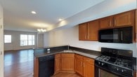 This two-story home offers a practical and cohesive layout with consistent finishes throughout. The main level features rich hardwood flooring that flows through the open living and dining areas, where natural light enters through large windows dressed with white horizontal blinds. A chandelier anchors the dining space, complementing the recessed lighting in the adjoining kitchen. The kitchen is well-equipped with warm-toned wood cabinetry, dark granite countertops, a stainless steel sink, and black appliances including a gas range, built-in microwave, and dishwasher. A convenient half bathroom on this level includes a pedestal sink, oval mirror, and hardwood flooring. The upper level hosts the bedrooms, each carpeted for comfort and served by natural light through window-covered blinds. One full bathroom features a dark granite vanity with wood cabinetry and a walk-in shower, while a second full bathroom offers a matching granite vanity and a tub-shower combination. Neutral wall tones and clean white trim are consistent throughout, giving the home a cohesive and move-in-ready appearance.