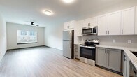 Located at 2024 US-70 W in Dickson, Tennessee, this well-appointed one-bedroom, one-bathroom unit offers a thoughtfully designed single-floor layout. The open-concept kitchen and living area serves as the heart of the unit, featuring light wood-tone luxury vinyl plank flooring that runs throughout the main living spaces. The kitchen is outfitted with a full suite of stainless steel appliances — including a refrigerator, electric range, microwave, and dishwasher — complemented by two-tone cabinetry with crisp white upper cabinets and gray lower cabinets, a classic subway tile backsplash, and granite-style countertops. A matte black faucet and hardware add a modern finishing touch. The living area is bright and open, with a large window offering views of the surrounding community's landscaped grounds. The bedroom provides a comfortable retreat with plush carpeting, a ceiling fan, a natural-light window, and an accent wall in a warm neutral tone. Three closets offer generous storage throughout the unit. The bathroom includes a tub/shower combo, a vanity with granite-style countertop and a backlit mirror, and matching luxury vinyl flooring. A dedicated laundry area rounds out the functional layout of this modern, move-in-ready unit.