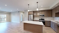 Located at 111 W Lamme St in Bozeman, Montana, this well-appointed 2-bedroom, 2-bathroom unit offers a thoughtfully designed single-floor layout with modern finishes throughout. The open-concept kitchen and living area serves as the heart of the home, featuring warm-toned cabinetry, a full suite of stainless steel appliances including a refrigerator, range, and microwave, a classic subway tile backsplash, and a large center island with a crisp white countertop and elegant pendant lighting. Light wood-style flooring flows throughout the main living areas, enhancing the bright and airy atmosphere. The living room receives generous natural light and provides direct access to a private balcony with outdoor views. The primary bedroom is a comfortable retreat, featuring recessed lighting and a walk-in closet with built-in shelving and hanging rods. The primary bathroom offers a dual-sink vanity with a wide mirror, warm cabinetry, and a glass-enclosed shower. The second bedroom features plush carpet flooring and a window with views of the surrounding neighborhood. Two closets provide ample storage. A hallway connects the rooms efficiently, completing a practical and polished floor plan ideal for everyday living in the heart of Bozeman.