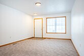 Located at 1013 E Monowau St in Tomah, Wisconsin, this single-floor, 2-bedroom, 1-bathroom home offers a practical and well-organized layout. The open living area features neutral carpet, white walls, and warm wood trim throughout, creating a clean and cohesive aesthetic. A sliding glass door at the far end of the living space fills the room with natural light and provides access to the outdoors.

The kitchen is a functional highlight of the home, featuring warm oak cabinetry with ample upper and lower storage, light countertops, a double-basin stainless steel sink beneath a window, and a peninsula that offers additional prep space and a casual dining option. Durable tile flooring and included appliances complete the kitchen. A sliding glass door adjacent to the kitchen adds further natural light.

Both bedrooms are carpeted and offer generous closet space, including sliding wood-panel closet doors. The primary bedroom is notably spacious with room for full furniture arrangements. The full bathroom features tile flooring, an oak vanity, and accessibility-friendly grab bars. A dedicated laundry area and five closets throughout the home provide excellent storage. The attached garage includes built-in shelving and an automatic opener, adding convenience to this well-appointed Tomah residence.