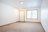 Located at 1013 E Monowau St in Tomah, Wisconsin, this single-floor, 2-bedroom, 1-bathroom home offers a practical and well-organized layout. The open living area features neutral carpet, white walls, and warm wood trim throughout, creating a clean and cohesive aesthetic. A sliding glass door at the far end of the living space fills the room with natural light and provides access to the outdoors.

The kitchen is a functional highlight of the home, featuring warm oak cabinetry with ample upper and lower storage, light countertops, a double-basin stainless steel sink beneath a window, and a peninsula that offers additional prep space and a casual dining option. Durable tile flooring and included appliances complete the kitchen. A sliding glass door adjacent to the kitchen adds further natural light.

Both bedrooms are carpeted and offer generous closet space, including sliding wood-panel closet doors. The primary bedroom is notably spacious with room for full furniture arrangements. The full bathroom features tile flooring, an oak vanity, and accessibility-friendly grab bars. A dedicated laundry area and five closets throughout the home provide excellent storage. The attached garage includes built-in shelving and an automatic opener, adding convenience to this well-appointed Tomah residence.