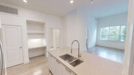 Located at 350 Village Dr in King of Prussia, PA, this one-bedroom, two-bathroom residence offers a thoughtfully designed single-floor layout with modern finishes throughout. The open-concept living and kitchen area features warm hardwood-style flooring, soaring ceilings, and recessed lighting complemented by sleek track fixtures. The kitchen is equipped with stainless steel appliances, including a refrigerator and microwave, cabinetry in a contemporary style, a mosaic tile backsplash, and a peninsula with countertop seating — ideal for casual dining or entertaining. The generously sized bedroom benefits from natural light through a large window fitted with blinds, offering views of lush greenery, and continues the warm hardwood-style flooring. The two bathrooms are finished to a high standard, featuring large-format marble-look tile flooring, clean white cabinetry with brushed nickel hardware, framed mirrors, and a tub-shower combo with floor-to-ceiling marble-style tile surround. A dedicated closet provides practical storage. The overall palette of crisp whites and warm neutrals creates a bright, clean, and inviting ambiance throughout this well-appointed King of Prussia residence.