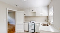 This single-story, 3-bedroom, 1-bathroom home in Fayetteville, NC offers a practical and efficiently organized layout. The interior is unified by warm hardwood flooring that extends throughout the living areas and bedrooms, complementing the neutral gray wall tones found across the home.

The front entry opens into a bright living area featuring two windows fitted with horizontal blinds, allowing natural light to fill the space. The kitchen is outfitted with white cabinetry extending to the ceiling, a white electric range, a stainless steel sink set in white countertops, and patterned tile flooring. A separate door in the kitchen provides exterior access. A full-size refrigerator occupies a dedicated area adjacent to the kitchen.

The spacious primary bedroom includes a ceiling fan, a closet, and connects conveniently to additional rooms via a hallway. The two secondary bedrooms also feature ceiling fans, hardwood floors, and windows with outdoor views. A connecting hallway links all rooms efficiently.

The bathroom is finished with classic white square wall tiles and a contrasting black tile border, housing a full tub with chrome fixtures. The overall aesthetic is clean, understated, and move-in ready.