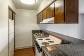 Located on City Boulevard West in Orange, California, this single-story unit presents a functional and straightforward layout with consistent wood-style flooring throughout. The open-concept design connects the kitchen directly to the living area, creating a cohesive flow across the main living space.

The kitchen features dark wood cabinetry overhead, granite-look countertops, a coil-top electric range, a double-basin sink, and a white refrigerator. A peninsula counter separates the kitchen from the living area, offering a practical divide while maintaining visual openness. A textured popcorn ceiling extends across the main living space, which benefits from natural light streaming through a full-width sliding glass door. This door opens to an outdoor patio area, providing a direct connection to the exterior.

A separate room off the main space features neutral gray walls, wood-style flooring, and an access panel on the wall. The bathroom includes a granite-look vanity countertop with an undermount sink, a mirrored medicine cabinet, a shower-tub combination, and sliding mirrored closet doors, maximizing storage and functionality. Overall, the unit offers a clean, practical living environment in a well-established Orange, CA location.