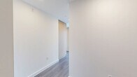 Located at 1331 Columbia Street in downtown San Diego, this high-rise unit offers a sleek, modern design with an open-concept layout spanning a comfortable single floor. The living room is anchored by dramatic floor-to-ceiling glass walls with black-framed sliding doors that open to sweeping panoramic views of the San Diego skyline and San Diego Bay, flooding the space with abundant natural light. Distinctive exposed concrete columns add an industrial-chic architectural element that contrasts beautifully with the warm grey hardwood-style flooring found throughout the main living areas. The kitchen features light wood flat-front cabinetry, white quartz countertops, a white tile backsplash, stainless steel appliances including a gas range, dishwasher, microwave, and refrigerator, all set against a backdrop of large windows framing city views. Two well-appointed bathrooms include floating wood vanities with white quartz counters, illuminated mirrors, and large-format tile flooring. The primary bathroom also features a glass-enclosed walk-in shower with full tile surround. A dedicated closet with built-in shelving and hanging rods provides organized storage. A clean, light-filled hallway connects the private areas of the home, completing this refined urban residence.
