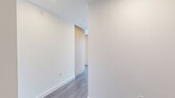 Located at 1331 Columbia Street in downtown San Diego, this high-rise unit offers a sleek, modern design with an open-concept layout spanning a comfortable single floor. The living room is anchored by dramatic floor-to-ceiling glass walls with black-framed sliding doors that open to sweeping panoramic views of the San Diego skyline and San Diego Bay, flooding the space with abundant natural light. Distinctive exposed concrete columns add an industrial-chic architectural element that contrasts beautifully with the warm grey hardwood-style flooring found throughout the main living areas. The kitchen features light wood flat-front cabinetry, white quartz countertops, a white tile backsplash, stainless steel appliances including a gas range, dishwasher, microwave, and refrigerator, all set against a backdrop of large windows framing city views. Two well-appointed bathrooms include floating wood vanities with white quartz counters, illuminated mirrors, and large-format tile flooring. The primary bathroom also features a glass-enclosed walk-in shower with full tile surround. A dedicated closet with built-in shelving and hanging rods provides organized storage. A clean, light-filled hallway connects the private areas of the home, completing this refined urban residence.