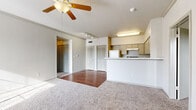 This single-story residence in Leander, Texas, offers a practical and functional layout across four bedrooms, two bathrooms, and dedicated laundry and hallway spaces. The open-concept living and kitchen area forms the heart of the home, where soft carpet transitions to hardwood-style flooring beneath a ceiling fan with a light fixture. A peninsula counter separates the kitchen from the living space, providing a casual dining or workspace surface. The kitchen is equipped with cabinetry in a neutral tone, a range with hood vent, and a refrigerator, with track lighting overhead adding a functional accent.

The four bedrooms are carpeted and filled with natural light through blinds-covered windows. Ceiling fans are present in multiple bedrooms, and each room connects to a closet, including walk-in options with wire shelving systems for organized storage. The primary bedroom features direct access to a walk-in closet and is comfortably proportioned.

The bathrooms include a tub-shower combination with white tile surround. The dedicated laundry room provides washer and dryer hookups on hardwood-style flooring. Throughout the home, neutral walls and light tones create a clean, move-in ready atmosphere.