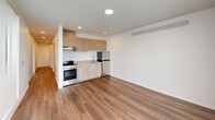 Located in Seattle's vibrant Wallingford neighborhood, this 2-bedroom, 2-bathroom unit offers a thoughtfully designed single-floor layout with modern finishes throughout. The open-concept kitchen and living area serves as the heart of the home, featuring warm wood-tone cabinetry, stainless steel appliances including a range and refrigerator, a single-basin sink, and durable hardwood-style flooring that extends through the main living spaces. Recessed lighting keeps the area bright and welcoming.

A central hallway connects the living area to the two bedrooms, each carpeted for comfort. The primary bedroom is generously sized, offering large windows that flood the room with natural light and provide views of the surrounding neighborhood. The second bedroom also benefits from a large window with an outdoor view. Both bedrooms feature closet storage, with a spacious walk-in closet offering wire shelving for added organization.

The two bathrooms are finished in a clean, contemporary style with light wood-tone vanities, stone-look countertops, and large mirrors. One bathroom includes a soaking tub with shower combination, while the second conveniently integrates a stacked washer and dryer unit alongside a walk-in shower. Three closets total provide ample storage throughout the home.