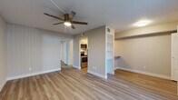 This single-floor residence offers a thoughtfully designed layout with a clean, modern aesthetic carried consistently throughout. The open living area is finished with light wood-style flooring, neutral warm-toned walls, and a textured ceiling, creating a bright and welcoming atmosphere. A ceiling fan provides comfort overhead, while a sliding glass door floods the space with natural light and provides access to an outdoor balcony area. A distinctive built-in shelving unit with a built-in desk nook serves as a functional divider between the living area and the kitchen, adding both character and practical storage.

The galley-style kitchen is efficiently designed and features stainless steel appliances including a refrigerator, electric range, microwave, and dishwasher, complemented by white cabinetry, a subway tile backsplash, and a stainless steel sink with modern fixtures.

The bedrooms continue the cohesive design language with the same light flooring, ceiling fans, and generous natural light provided by wide windows with blinds. Each bedroom includes closet space, with one featuring a walk-in closet visible through an open door.

The bathroom is clean and straightforward, featuring a tiled shower-tub combination, white fixtures, and wood-style flooring that ties into the rest of the home. Overall, the space presents a fresh, functional, and move-in ready environment.
