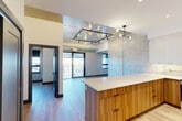 Located at 1624 Lauzon Rd in Windsor, Ontario, this thoughtfully designed one-bedroom, one-bathroom unit offers a contemporary living experience across a well-utilized single floor. The open-concept kitchen and living area serves as the heart of the space, featuring a striking kitchen island with warm wood-grain cabinetry and a crisp white quartz countertop. The kitchen is fully equipped with stainless steel appliances, white upper cabinetry, a decorative patterned tile backsplash, and under-cabinet lighting. A floor-to-ceiling marble-effect accent wall adds a sophisticated touch to the main living area, which is illuminated by modern track and pendant lighting. Light wood-look flooring flows throughout, complementing the bright, neutral palette. The living and dining areas benefit from large sliding glass doors that open onto a private balcony, offering expansive views of the surrounding Windsor neighbourhood beneath open skies. The bedroom provides a comfortable retreat with natural light from a dedicated window and clean, high walls. The bathroom features a soaker tub finished with large-format stone-look tiles and sleek matte black fixtures. An in-unit laundry area adds everyday convenience to this well-appointed modern home.