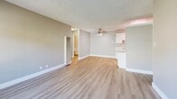 Located at Carter Drive in South San Francisco, this single-story, one-bedroom residence offers a well-organized layout designed for functional everyday living. The combined kitchen and living area forms the heart of the home, featuring light wood-toned luxury vinyl plank flooring that runs throughout. The living room is bright and open, anchored by a ceiling fan and neutral gray-toned walls that create a calm, contemporary atmosphere. Adjacent to the living space, the galley-style kitchen is efficiently arranged with white cabinetry offering generous storage, light countertops, a stainless steel sink, and white appliances including a gas range with overhead microwave and a full-sized refrigerator. The bedroom is a comfortable retreat featuring a large window that admits natural light and offers views of surrounding greenery. Its neutral wall tones and continued LVP flooring maintain a cohesive aesthetic throughout. Two dedicated closets provide practical storage solutions, one of which features wire shelving for organized use. Textured ceilings add a subtle architectural detail throughout the space. Clean white baseboards and trim throughout provide crisp contrast to the warm flooring and muted wall colors, resulting in a tidy, move-in ready residence.