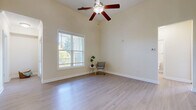Located at 5001 Ballantyne Drive in Simpsonville, SC, this single-floor, three-bedroom, one-bathroom home offers a comfortable and well-organized layout. Light hardwood-style flooring runs throughout, complementing the warm, neutral wall tones that create a bright and inviting atmosphere across all rooms.

The combined kitchen and living area serves as the heart of the home. The kitchen features warm wood cabinetry, granite-style countertops, and black appliances including a full-size refrigerator and range. The living area is generously proportioned, with vaulted ceilings, a ceiling fan, and large windows that allow abundant natural light and outdoor views.

The spacious primary bedroom is notably large, with room for ample furnishings, and connects directly to a closet and the full bathroom. The bathroom includes a rich wood vanity with granite-style countertops and a shower-tub combo. Two additional bedrooms each feature pendant lighting, windows with blinds offering natural light, and convenient closet access.

A dedicated laundry room includes washer and dryer hookups. Two hallways connect the rooms efficiently throughout the home. Three closets provide practical storage. The overall ambiance is clean, airy, and move-in ready, making this a well-rounded and functional single-level home.