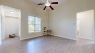 Located at 5001 Ballantyne Drive in Simpsonville, SC, this single-floor, three-bedroom, one-bathroom home offers a comfortable and well-organized layout. Light hardwood-style flooring runs throughout, complementing the warm, neutral wall tones that create a bright and inviting atmosphere across all rooms.

The combined kitchen and living area serves as the heart of the home. The kitchen features warm wood cabinetry, granite-style countertops, and black appliances including a full-size refrigerator and range. The living area is generously proportioned, with vaulted ceilings, a ceiling fan, and large windows that allow abundant natural light and outdoor views.

The spacious primary bedroom is notably large, with room for ample furnishings, and connects directly to a closet and the full bathroom. The bathroom includes a rich wood vanity with granite-style countertops and a shower-tub combo. Two additional bedrooms each feature pendant lighting, windows with blinds offering natural light, and convenient closet access.

A dedicated laundry room includes washer and dryer hookups. Two hallways connect the rooms efficiently throughout the home. Three closets provide practical storage. The overall ambiance is clean, airy, and move-in ready, making this a well-rounded and functional single-level home.