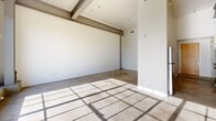 This 590 square foot apartment in Sacramento combines modern design with industrial elements. The single-floor layout maximizes space efficiency, featuring an open concept that seamlessly integrates living areas. The kitchen is a standout, boasting sleek cabinetry in a warm wood tone, contrasting beautifully with stainless steel appliances and a long, uninterrupted countertop. Glass-fronted upper cabinets add a touch of elegance while maintaining the airy feel.

The bathroom continues the contemporary theme with a glass-enclosed shower, modern fixtures, and a floating vanity that matches the kitchen cabinetry. Tile work in neutral tones adds visual interest and practicality.

Throughout the apartment, high ceilings with exposed beams and ductwork lend an industrial chic vibe, while large windows flood the space with natural light. The concrete floors, while showing some wear, contribute to the urban loft aesthetic. An empty room, likely intended as a bedroom or living area, showcases the potential for personalization.

The property's location in downtown Sacramento (1530 J St) places it at the heart of urban living, ideal for those seeking a city lifestyle. This apartment strikes a balance between functionality and style, perfect for the modern urbanite.
