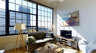 Situated in the heart of Columbus, Ohio, this single-floor loft-style space at 272 S Front St delivers a striking blend of industrial character and modern comfort. The living area is anchored by expansive floor-to-ceiling multi-pane windows with bold black steel frames, flooding the interior with abundant natural light and offering captivating views of the Columbus skyline and surrounding cityscape. The soaring ceiling height enhances the sense of openness, while original architectural details — including a decorative column capital — speak to the building's historic character. Warm hardwood flooring runs throughout, complementing the bright, sun-drenched atmosphere created by the oversized windows. The space is thoughtfully laid out to maximize both functionality and aesthetic appeal, with a comfortable living area that takes full advantage of its urban panorama. Vibrant artwork adorns the walls, adding a creative energy that pairs naturally with the loft's industrial bones. Overall, the space exudes a dynamic, cosmopolitan ambiance, ideal for those who appreciate architectural heritage combined with the energy of downtown Columbus living.