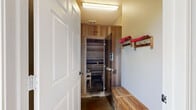 Located at Heron Pointe in Nashville, Tennessee, this compact wellness facility is thoughtfully designed to deliver a complete sauna experience. The space is organized into distinct functional zones connected by a corridor with polished concrete floors that lend a clean, durable aesthetic throughout.

At the heart of the facility is a cedar-lined sauna room, accessible through a glass-paneled door. The interior is fully clad in warm, horizontal wood planking that lines both the walls and the tiered bench seating, creating an enveloping atmosphere of natural warmth. The multi-level benches allow users to choose their preferred intensity level, while the wood floor grating underfoot adds to the classic sauna experience.

Adjacent to the sauna is a dedicated changing and preparation area. A slatted wooden bench with under-seat storage provides a convenient place to sit and prepare, while wall-mounted wooden coat and towel hooks keep essentials within easy reach. Overhead, bright flush-mounted lighting ensures the area is well lit.

The connecting hallway opens to a bright anteroom featuring large grid-pane windows and a glass exterior door that invite natural light and offer views of the surrounding greenery. A recessed fire extinguisher cabinet is mounted on the wall, reflecting attention to safety. The overall ambiance is practical yet welcoming, making this a well-equipped spot for relaxation and recovery.