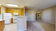 Located at 1441 Santa Lucia Rd in Chula Vista, California, this single-floor residence offers a well-designed, functional layout with a warm, neutral color palette throughout. The open-concept kitchen flows seamlessly into the living area, creating an inviting and practical shared space. The kitchen is equipped with wood-toned cabinetry, light stone countertops, white appliances including a gas range, over-the-range microwave, and refrigerator, as well as a peninsula that provides additional prep and serving space. A skylight above the kitchen brings in natural light, enhancing the brightness of the area. The living space features soft carpeting and multiple windows fitted with vertical blinds, allowing natural light to filter in alongside views of the lush, tree-lined surroundings. The bedrooms are generously sized, each with plush carpet and windows overlooking the greenery outside. One bedroom includes a spacious walk-in closet with built-in shelving and hanging rods. The full bathroom is finished with tile flooring, a wood-toned vanity with a stone-top sink, a large mirror, and a tub-shower combination. A dedicated in-unit laundry closet houses a full-sized washer and dryer. An outdoor railed area overlooks a landscaped setting with mature palm and shade trees.