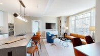 Located in Chicago's vibrant Streeterville neighborhood, this thoughtfully designed residence at 514 N Peshtigo Ct offers a seamless blend of contemporary style and urban sophistication. The entry foyer sets an inviting tone, featuring warm neutral walls, light wood-style flooring, and curated artwork that leads gracefully into the main living areas.

The open-concept living and dining space is bright and generously proportioned, anchored by floor-to-ceiling windows that frame sweeping views of the Chicago skyline and Lake Michigan. The living area features a tan leather sofa, vibrant accent chairs in teal and rust, and a built-in shelving nook, all accented by elegant sheer drapery.

The kitchen is well-appointed with crisp white cabinetry extending to the ceiling, dark stone countertops, a large center island with bar seating, stainless steel appliances including a gas cooktop and double wall ovens, and a clean glass tile backsplash.

The primary bedroom is a serene retreat with expansive city and lake views, plush carpeting, and soft, neutral tones. A secondary bedroom functions as a flexible space with a daybed and open closet system. Bathrooms are finished with herringbone-patterned tile flooring, marble-topped white vanities, and clean, modern fixtures throughout.