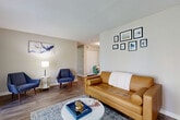 This efficiently laid-out one-bedroom, one-bathroom unit spans a single floor and is designed to maximize functionality without sacrificing comfort. The entrance opens into a corridor that leads to the main living areas, all finished with durable wood-style flooring throughout. The living room is a welcoming space featuring French doors flanked by sidelights that invite generous natural light and offer views of the outdoors. Neutral-toned walls and a textured ceiling complement the open feel of the room.

The galley-style kitchen is well-appointed with dark espresso cabinetry, white quartz countertops, a subway tile backsplash, stainless steel appliances including a dishwasher and electric range, and an undermount sink. It connects directly to a dedicated dining area, which includes a closet for additional storage.

The bedroom is carpeted and comfortably proportioned, offering a quiet retreat with its own natural light source. The bathroom features a dark wood vanity with white countertop, an undermount sink, and a large mirror, maintaining a consistent, clean aesthetic throughout. The unit offers a practical and cohesive living environment overall.