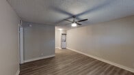 This single-floor unit offers a clean, modern aesthetic throughout, highlighted by warm-toned laminate flooring and neutral gray walls that create a bright, cohesive atmosphere. The open living area is a welcoming space, featuring a ceiling fan with integrated lighting and a textured ceiling. A window with horizontal blinds allows natural light to filter in, and a dedicated entry door provides direct access to the unit.

The kitchen is a standout feature, showcasing white shaker-style cabinetry, a classic subway tile backsplash, and stainless steel appliances including an electric range, over-the-range microwave, and refrigerator. A deep single-basin sink and ample counter space make this kitchen both functional and visually appealing.

Adjacent to the living area, a hallway leads to the bedroom, which continues the laminate flooring and neutral palette. The bedroom is fitted with its own ceiling fan and a window with blinds, ensuring comfort and natural light. The bathroom is appointed with a full tub and shower combo featuring brushed nickel fixtures and a grab bar, paired with clean white surrounds and matching flooring. A convenient in-unit laundry area with a washer rounds out the practical amenities of this thoughtfully designed space.