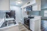 This single-story unit in Memphis, Tennessee offers a thoughtfully updated interior with a cohesive, neutral color palette throughout. Light-toned luxury vinyl plank flooring runs continuously across the living areas and bedroom, providing a clean, modern aesthetic that enhances the sense of openness.

The kitchen is a standout feature, equipped with white shaker-style cabinetry, marble-look countertops, a double-basin stainless steel sink, and a subway tile backsplash. Black appliances, including a refrigerator and dishwasher, provide contrast against the bright cabinetry. A peninsula counter offers additional prep space and creates a natural division between the kitchen and living area.

The living area benefits from natural light through a window fitted with horizontal blinds. The bedroom is similarly well-lit, featuring a ceiling fan with a light fixture, a window allowing natural light, and two closets providing ample storage. The textured ceiling adds subtle architectural detail throughout the unit.

The bathroom is finished in a clean, all-white scheme, featuring a tiled tub-shower combination, a toilet, and light wood-toned flooring that complements the rest of the unit. Overall, the space presents a practical and updated environment suitable for comfortable single-occupant living.