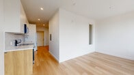 Located at 345 N Queen St in Lancaster, PA, this thoughtfully designed one-bedroom, one-bathroom unit offers a modern living experience with clean lines and a bright, contemporary aesthetic throughout. Light-toned hardwood flooring flows seamlessly across the entire space, complementing the crisp white walls and recessed lighting that keep the interior feeling open and airy.

The open-concept living area connects directly to the kitchen, creating an efficient and cohesive layout. The kitchen is outfitted with stainless steel appliances—including a range, dishwasher, and over-the-range microwave—paired with warm wood lower cabinetry, white upper cabinets, white quartz countertops, and a sleek tile backsplash in a soft blue-gray vertical pattern.

The living room benefits from floor-to-ceiling windows that invite an abundance of natural light and frame elevated views of the Lancaster cityscape. The bedroom is a compact, well-appointed space with its own large window and city views, maintaining the same light and minimal aesthetic.

The bathroom features a floating wood vanity with a white countertop, a large mirror cabinet, and large-format neutral floor tiles, along with a walk-in shower. Clean hardware and understated finishes throughout give the bathroom a polished, modern feel that matches the rest of the unit.