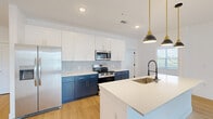 Located at 7130 Adelo Point in Colorado Springs, CO, this thoughtfully designed single-floor home offers three bedrooms, three bathrooms, and a cohesive modern aesthetic throughout. Light-toned luxury vinyl plank flooring flows seamlessly across every room, complemented by crisp white walls and clean architectural lines.

The open-concept kitchen is a standout feature, boasting a two-tone design with bold navy lower cabinets, white upper cabinetry, and a geometric hexagonal tile backsplash. A large center island with a white quartz countertop and an undermount sink serves as the heart of the space, while stainless steel appliances and stylish pendant lighting complete the look.

The bedrooms are bright and comfortable, each featuring ceiling fans and generous natural light from well-placed windows. Each of the three bedrooms is paired with its own closet. The bathrooms are finished with navy vanities, white quartz countertops, large-format tile surrounds, glass-enclosed showers with matte black fixtures, and illuminated mirrors — delivering a sleek, modern feel.

A dedicated in-unit laundry room with built-in shelving adds everyday convenience. The home's clean, contemporary design and efficient single-floor layout make it an exceptionally functional and stylish residence in Colorado Springs.