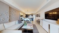 This elegantly appointed high-rise residence offers a seamless blend of modern design and refined comfort across a single, well-organized floor. The open-plan living and dining area serves as the heart of the home, anchored by floor-to-ceiling windows and sliding glass doors that flood the space with natural light and frame sweeping panoramic city views. The living room features a plush sectional sofa, a sleek marble-topped coffee table, and a distinctive decorative wall adorned with sculptural accents, adding an artistic focal point to the space. A stylish chandelier illuminates the dining area, which flows effortlessly into the dark-cabinetry kitchen equipped with stainless steel appliances and a generous island.

The primary bedroom enjoys its own dramatic floor-to-ceiling windows with expansive city vistas, plush carpeting, and direct access to a spa-inspired ensuite featuring full marble wall and floor cladding, a frameless glass walk-in shower, and a built-in bench. A second bedroom also benefits from large windows with skyline views, while a third bedroom offers a quieter, textured aesthetic. The secondary bathroom is finished with neutral tile, a soaker tub, and a modern floating vanity. A dedicated in-unit laundry closet with stacked washer and dryer adds everyday convenience to this elevated urban residence.