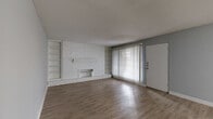 Located at 313 Sunnyside St in Houston, TX, this single-story, 2-bedroom, 1-bathroom home offers a practical and comfortable layout. The living room serves as the heart of the home, showcasing a striking white-painted brick fireplace flanked by built-in bookshelves — a standout architectural detail. Large sliding glass doors with vertical blinds allow natural light to fill the space, which features durable wood-look flooring throughout the main areas. The galley-style kitchen is efficiently designed with gray cabinetry, white countertops, a stainless steel sink, and white appliances including a range and refrigerator, all set on wood-look flooring. A hallway connects the main living areas to the private quarters. Both bedrooms are carpeted and painted in a neutral gray palette; the primary bedroom offers a ceiling fan and a window with outdoor views, while the second bedroom also enjoys natural light. Each bedroom is served by its own closet, with the primary closet offering a walk-in configuration complete with built-in shelving and hanging rods. The full bathroom includes a single vanity with a wide mirror, and a shower-tub combination. Throughout, the home maintains a clean, neutral aesthetic suited for a variety of furnishing styles.