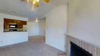 This single-floor residence offers a practical and functional layout with a warm, understated aesthetic. The living area serves as the heart of the home, featuring wall-to-wall carpeting that adds comfort underfoot and a cozy, neutral tone throughout. A standout feature is the brick fireplace, complete with a tiled hearth and mantle, providing a natural focal point and a welcoming atmosphere.

The ceiling rises to a vaulted height, enhancing the sense of openness in the main living space, and is fitted with a ceiling fan to ensure year-round comfort. The transition from the living area to the kitchen is seamless, with an open-concept design that connects the two spaces effortlessly. The kitchen features dark wood cabinetry and a raised counter or breakfast bar, offering both functionality and a casual dining option.

The interior is finished in clean, neutral white tones throughout, creating a bright and versatile canvas that accommodates a wide range of furnishing styles. The overall ambiance of the home is simple, practical, and move-in ready, making it a solid and comfortable living space.