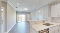 Located at 2421 Bristol Road in Warrington, PA, this thoughtfully designed single-floor residence offers three bedrooms, three bathrooms, and four closets within a well-appointed layout. The open-concept living and kitchen area is anchored by wood-look flooring and neutral gray walls, creating a bright, cohesive atmosphere. A sliding glass door floods the living space with natural light and provides outdoor access. The kitchen is a standout feature, showcasing crisp white shaker cabinetry, a striking marble-veined quartz backsplash and countertops, stainless steel appliances including a gas range, built-in microwave, and French door refrigerator, plus a peninsula with bar-top seating. Crown molding and recessed lighting add refined detail throughout. Each bedroom offers wood-look flooring, soft neutral tones, and generous windows with serene outdoor views of the surrounding landscape. The spacious primary bedroom is well-sized with access to dedicated closet space. All three bathrooms are finished with large-format marble-look porcelain tile flooring and tub surrounds, white vanities with quartz countertops, and brushed nickel fixtures, delivering a clean, upscale aesthetic. The overall ambiance is modern, fresh, and move-in ready.