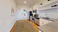 Located at 519 Porter St in Richmond's 23224 zip code, this single-floor unit showcases a clean, modern aesthetic with consistent design details throughout. The living area is bright and welcoming, featuring warm hardwood flooring, large windows that frame views of the Richmond skyline, and an open layout that promotes a comfortable flow. The space is well-proportioned, offering room for relaxed seating arrangements centered around a glass coffee table and a wall-mounted television.

The kitchen is efficiently designed with white cabinetry, open shelving, a white subway tile backsplash, and gray countertops. Stainless steel appliances — including a range, microwave, refrigerator, and dishwasher — provide full functionality, while warm hardwood flooring ties the space to the adjoining living area. A pendant light adds a finishing decorative touch.

The bedroom is a calm, neutral retreat with plush carpeting, a ceiling fan, and a window with city views. An adjacent bathroom features a white vanity with gray countertops, a soaking tub with shower, and light tile flooring, maintaining the unit's cohesive, contemporary palette throughout.