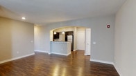 Located at 11289 E Hamilton Crest Blvd in Fishers, Indiana, this single-floor residence offers a thoughtfully designed open-concept layout that maximizes functionality and flow. Rich hardwood-style flooring extends throughout the main living areas, providing warmth and a polished aesthetic.

The living area is generously proportioned, with neutral gray walls and clean white trim that create a bright, welcoming atmosphere. A defining architectural feature is the elegant arched pass-through that connects the living space to the kitchen, adding visual interest while maintaining an open feel.

The kitchen is well-appointed with dark espresso cabinetry, granite-style countertops, and stainless steel appliances including a refrigerator. Pendant lighting accents the kitchen area, enhancing both function and ambiance. The kitchen layout is efficient, offering ample cabinetry and counter workspace.

A private entry door is visible from the main living area, contributing to the sense of privacy and accessibility within the home. The consistent use of neutral tones throughout — from the flooring to the wall colors — creates a cohesive and move-in ready environment. Overall, this Fishers residence combines practical design with attractive finishes, making it a comfortable and stylish single-floor living space.