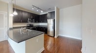 This single-floor residence offers a thoughtfully designed layout that balances open living spaces with functional private areas. The main living area features gleaming hardwood floors that extend throughout, neutral-toned walls, and ceiling fans that enhance airflow and comfort. Large sliding glass doors with vertical blinds open to an outdoor view, flooding the space with natural light and creating a seamless connection to the exterior.

The kitchen is a standout feature, equipped with dark espresso cabinetry, granite countertops, a subway tile backsplash, and a full suite of stainless steel appliances including a refrigerator, range, and microwave. Track lighting overhead and an integrated sink at the peninsula add both style and practicality.

The bedrooms are carpeted for warmth and comfort, with ceiling fans and large windows fitted with horizontal blinds that allow for ample natural light and outdoor views of the surrounding community.

The bathrooms are finished with tile flooring and clean, contemporary fixtures. One bathroom features a dark-cabineted vanity with a granite countertop and a tiled shower-tub combination, while another offers a glass-enclosed walk-in shower with large-format tile surround and a built-in niche. A louvered closet door provides additional storage. Overall, the space presents a clean, modern aesthetic throughout.