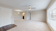 This single-floor 1-bedroom, 1-bathroom unit is thoughtfully laid out to maximize comfort and functionality. The open living and dining area features soft, neutral-toned carpet, a ceiling fan with light fixture, and a large window fitted with blinds that invites natural light while offering views of the surrounding greenery. A decorative chair rail adds a subtle architectural detail to the living space. The transition to the kitchen is marked by warm wood-style flooring, leading into a galley-style kitchen equipped with white shaker cabinetry, dark granite-style countertops, a stainless steel sink, and black appliances including a refrigerator, range, and dishwasher. A pendant light fixture illuminates the dining area just off the kitchen. The bedroom is generously sized with plush carpeting, a ceiling fan, and a window that provides natural light. It includes access to a spacious walk-in closet outfitted with dual shelving and hanging rods on both sides, offering ample storage. The full bathroom features a tiled tub-shower combination with chrome fixtures and wood-style flooring, complemented by white cabinetry. Clean, neutral finishes throughout give the unit a bright and move-in-ready feel.